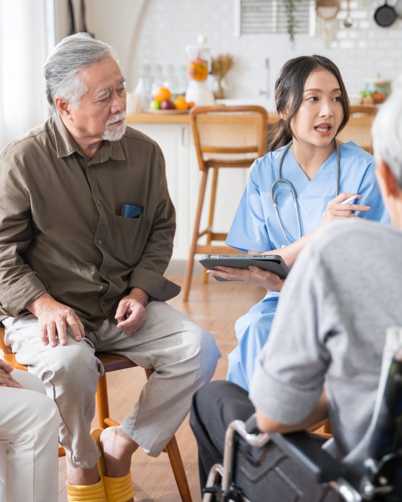 Group of Asian senior people sit in a circle in a nursing home and listen to nurse during a group elderly therapy session.